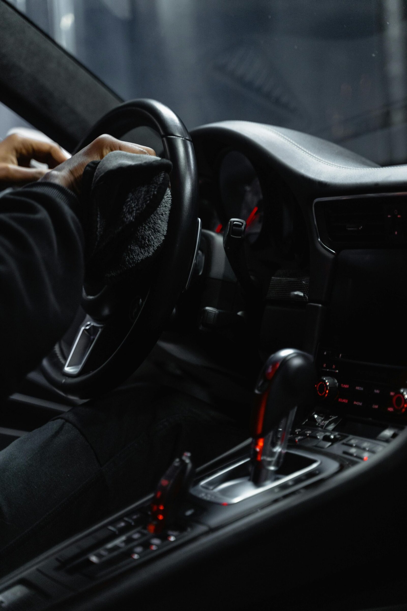 Close-up of a person cleaning a car's dashboard and steering wheel, focused on interior maintenance.